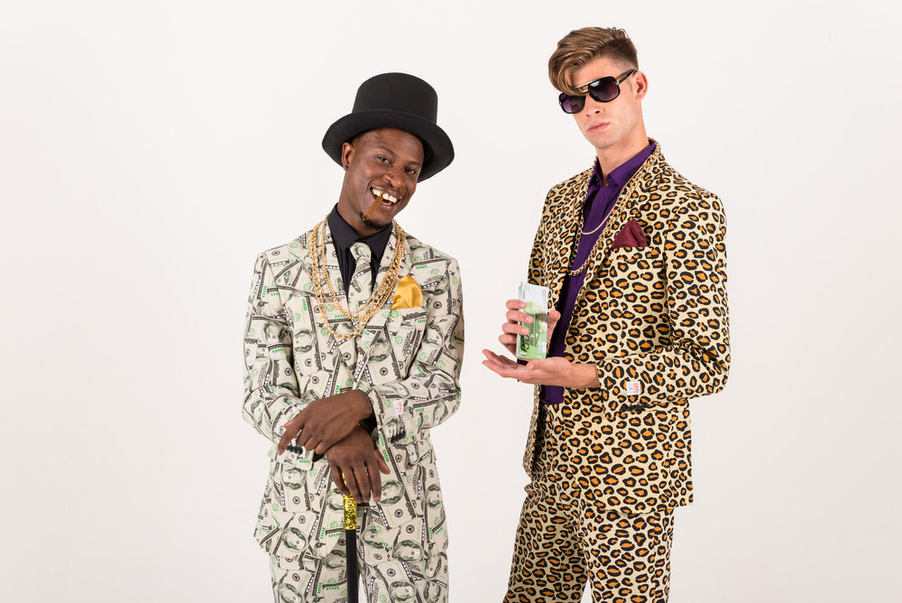 Two men posing in bold suits, one in a money-print suit with a top hat and the other in a leopard-print suit holding cash.