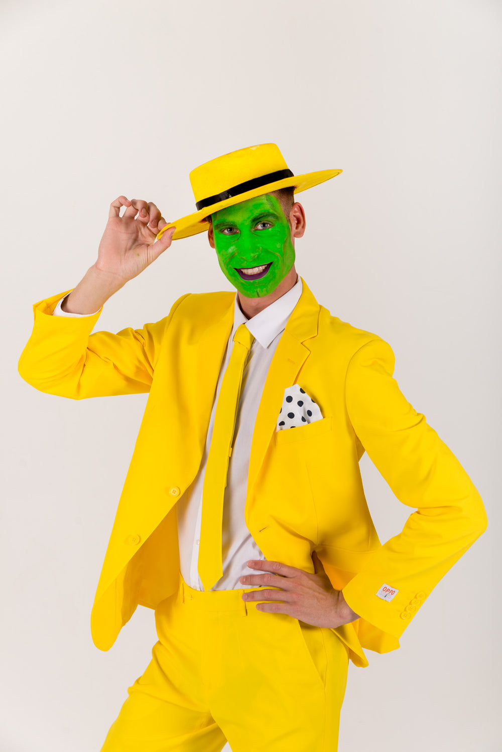 Man in a bright yellow suit and matching hat with green face paint and a polka-dot pocket square. Imitating the movie character from the Mask.