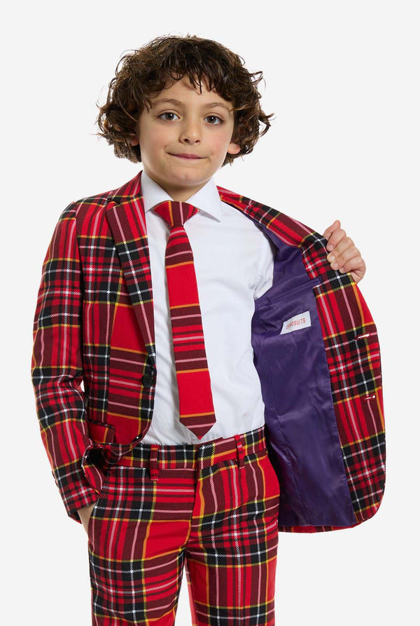 Child wearing a red plaid Christmas suit with a white shirt and purple vest on a white background