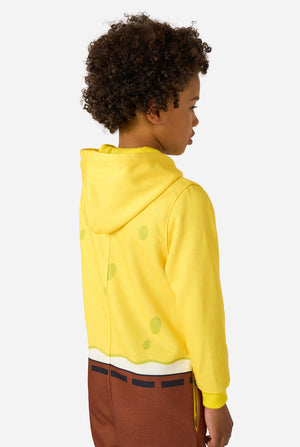 Child wearing a yellow Spongebob onesie with a white shirt and brown pants on a light gray background