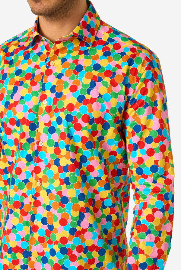Person wearing a colorful polka dot confetti shirt with a plain background, close-up.