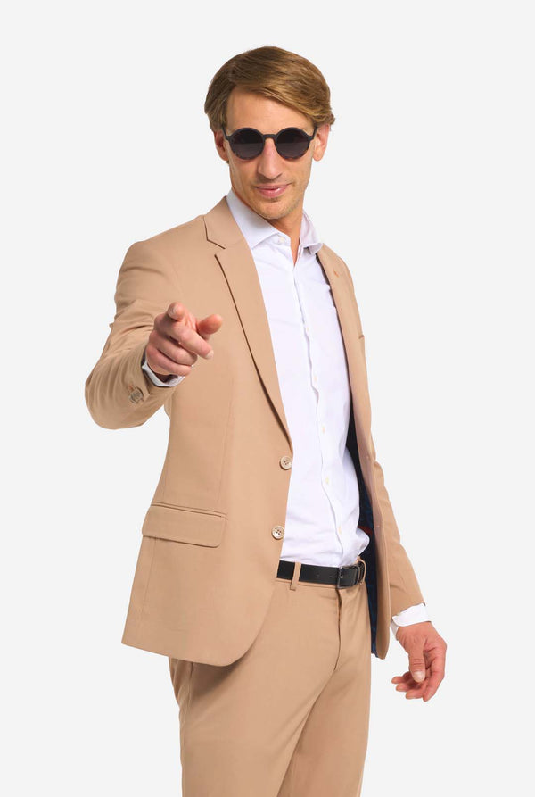 Man wearing a beige suit and sunglasses on a white background
