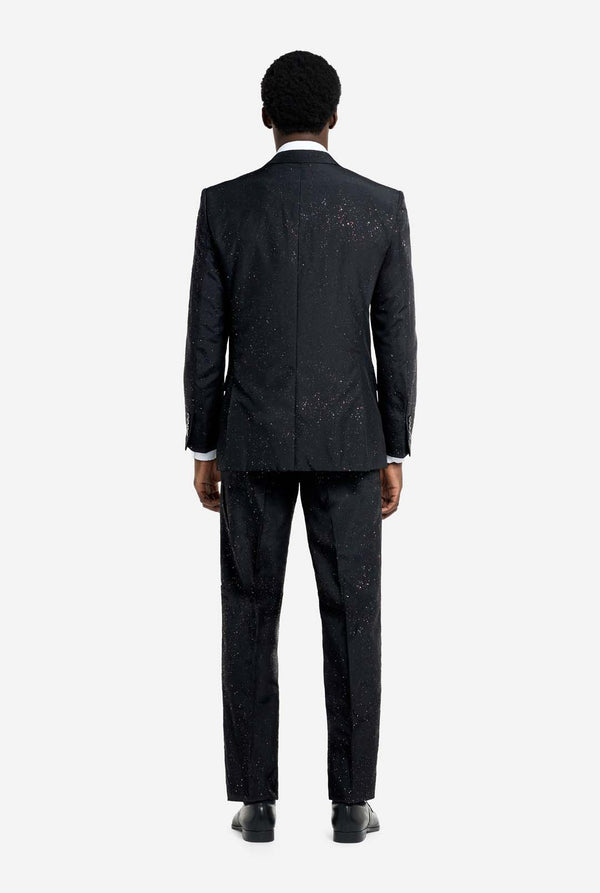 Image of a man wearing an OppoSuits Glitzy Glitter men's suit with glitters and white men's shirt. Suit consist of pants, jacket and tie. View from the back.