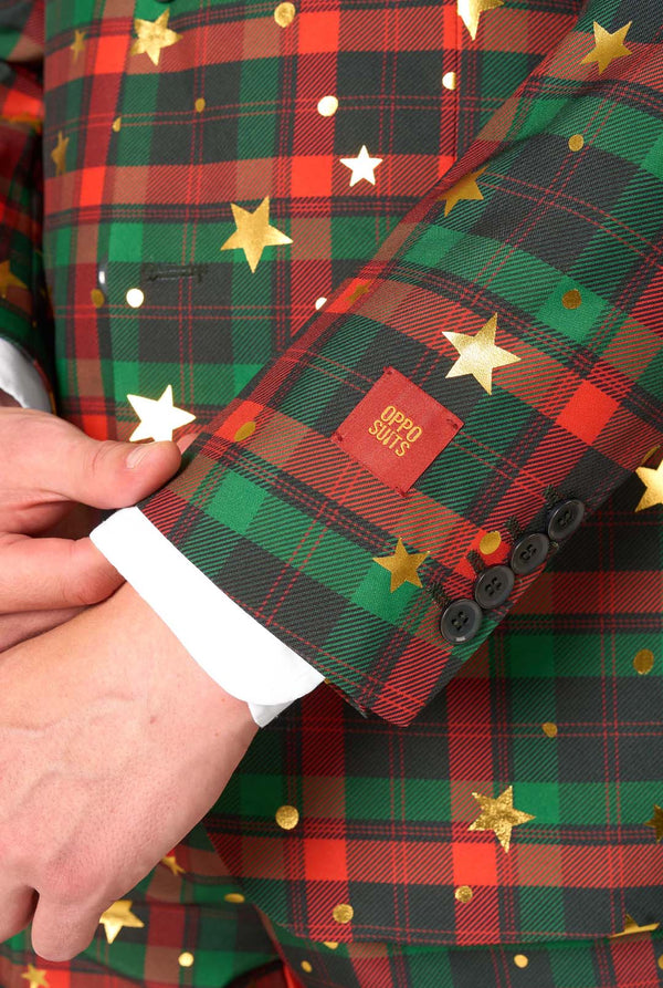 Green plaid fabric with gold stars and a visible brand label, held by a hand.