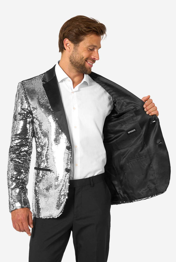 Man holding a silver sequin jacket over a black one against a white background