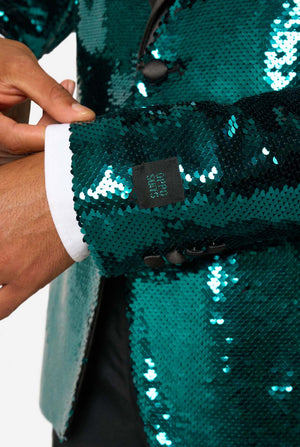 Close-up of a person wearing a teal sequin jacket with a visible brand tag.