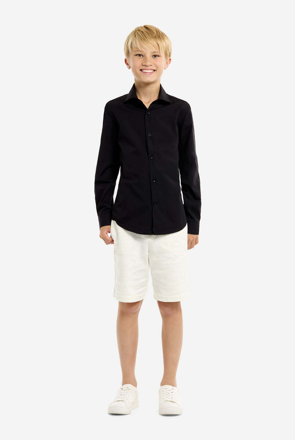 Young boy wearing a black shirt and white shorts on a white background