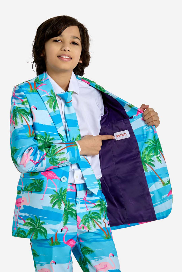 Child wearing a colorful suit with palm tree and flamingo pattern, pointing to the inside pocket.