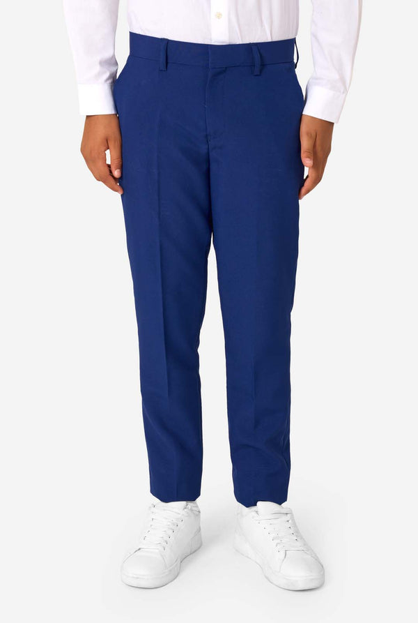 Person wearing blue dress pants with a white shirt and white shoes on a white background
