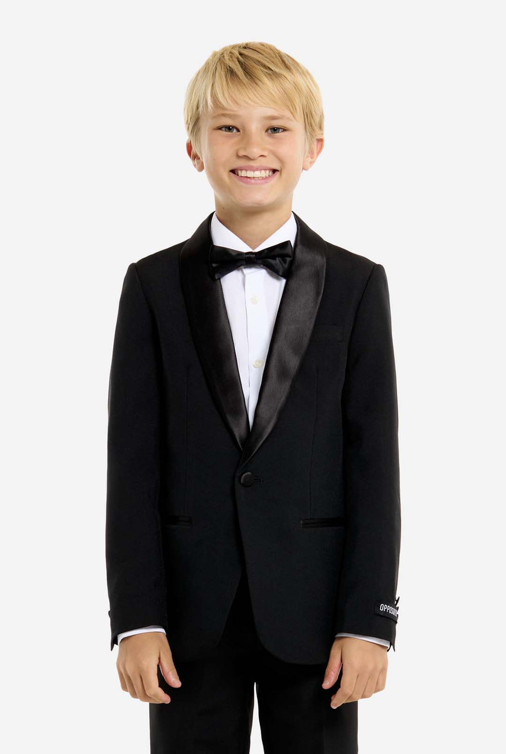 Young boy wearing a black tuxedo with a white shirt and black bow tie on a white background