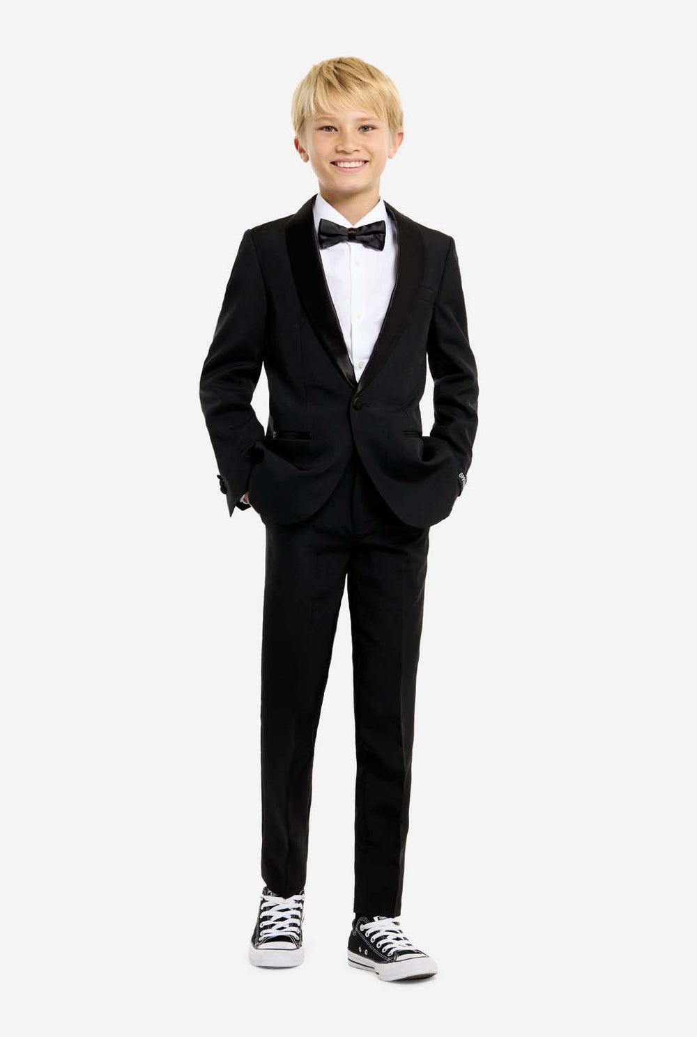 Young boy wearing a black tuxedo with a white shirt and black bow tie on a white background