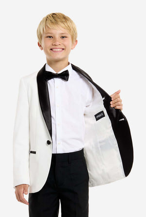 Young boy wearing a white tuxedo with black bow tie and pants on a white background. One side of the jacket open.