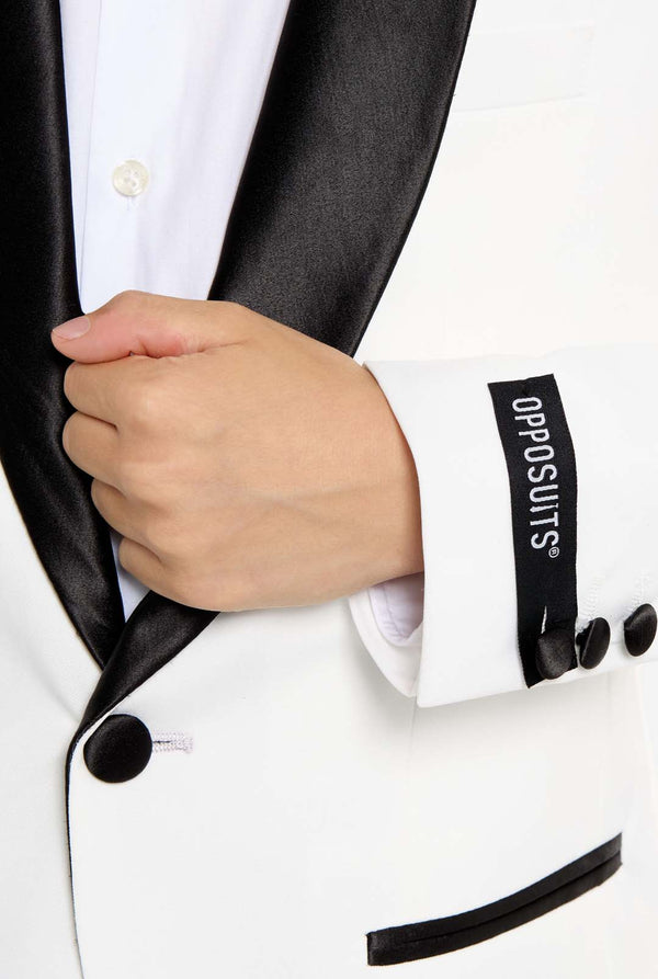 Person wearing a white tuxedo with black lapels and a visible 'Oposuits' tag.