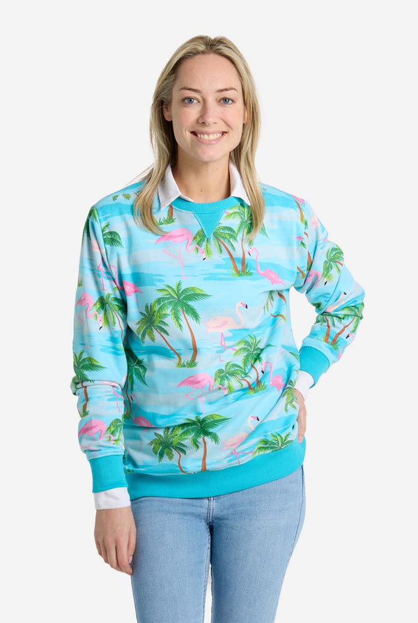 Woman wearing a tropical-themed sweatshirt with palm trees and flamingos on a white background