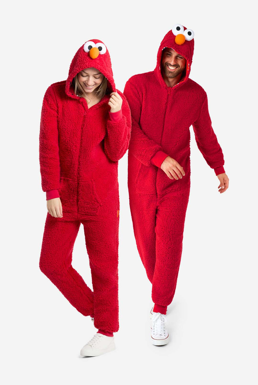 A man and a woman are dressed in a red Elmo-themed onesie. The overall design mimics the look of the Sesame Street character Elmo. The background is plain, putting focus on the costume.