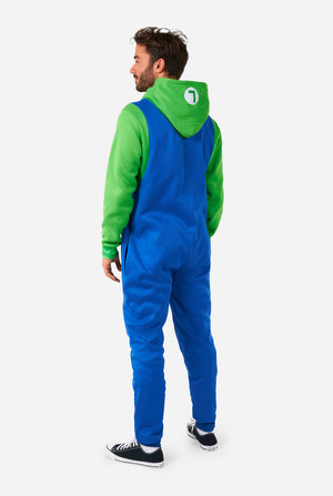 A man is dressed in a Luigi-themed onesie. The outfit looks as a bright green hoodie with an "L" symbol on the hood and blue overalls with large yellow buttons on the straps. View from the back and the hood laying flat on the back. The overall design mimics the look of the popular video game character Luigi, with contrasting green and blue colors. The background is plain, putting focus on the costume and the man's pose.