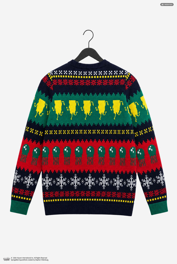 A long-sleeve knit sweater shown from the back, hanging on a black hanger against a light gray background. The sweater features a festive multicolor holiday pattern with rows of yellow Christmas trees, green ornaments, red snowflakes, and white snowflakes on a dark navy base.