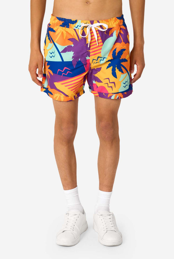 Person wearing colorful tropical-themed shorts on a white background