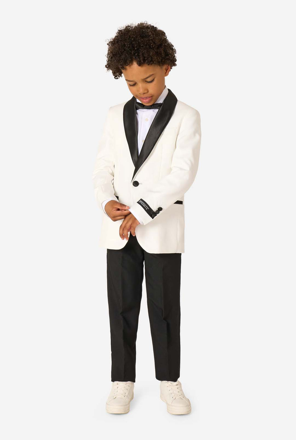 Child wearing a white tuxedo with black lapels and bow tie on a white background