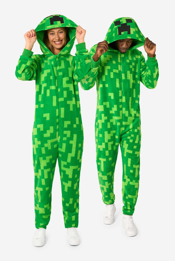 Two people wearing green pixelated Creeper onesies on a white background