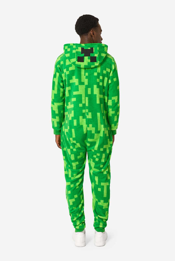 Person wearing a green pixelated Creeper onesie on a white background