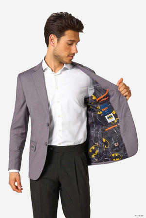 Man wearing a gray blazer with a Batman-themed inside peeking out, on a white background