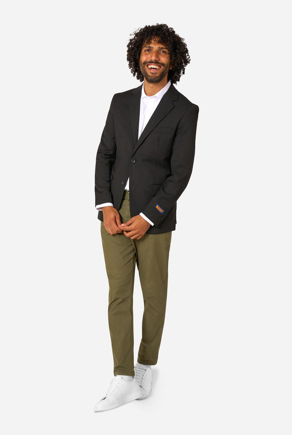 Man wearing a black blazer over a white shirt with green pants on a white background