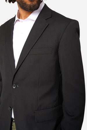 Black suit jacket worn by a person on a white background. Close up of the chest