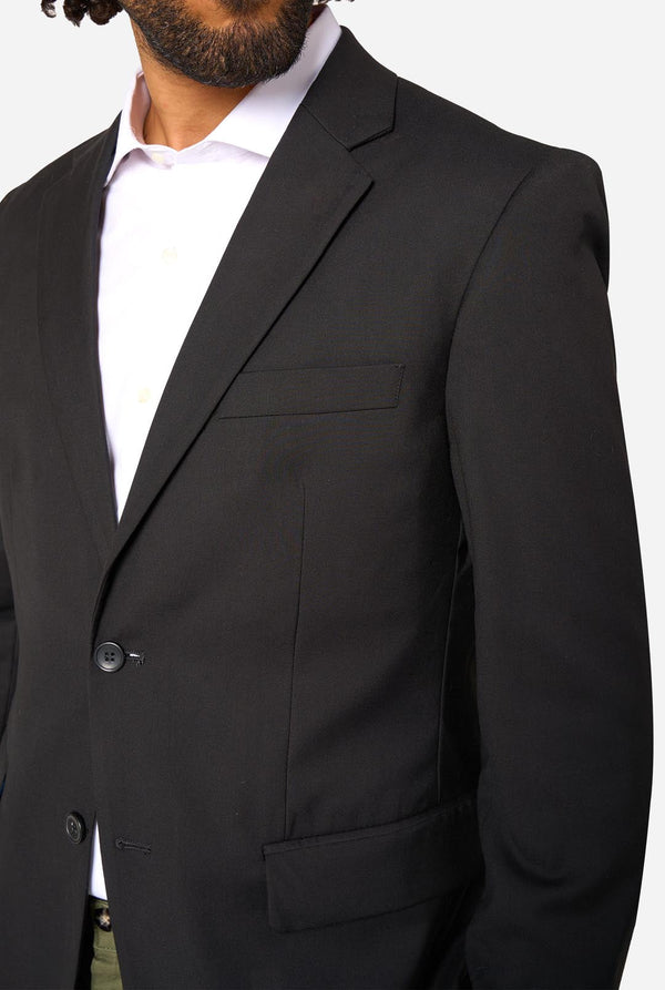 Black suit jacket worn by a person on a white background. Close up of the chest