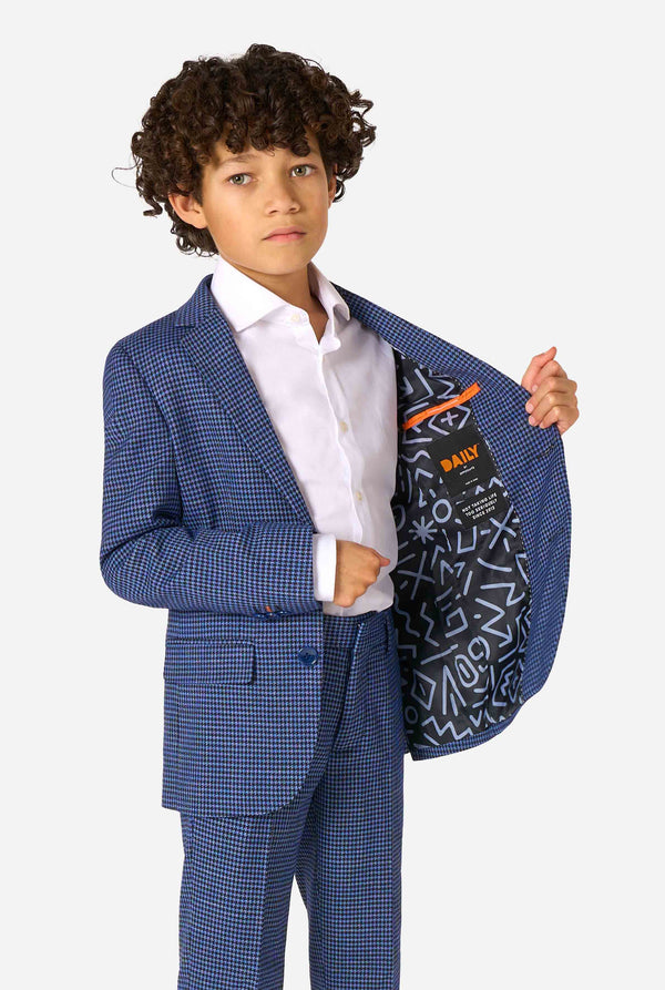 Child wearing a blue checkered suit holding the jacket open and showing visible branding.