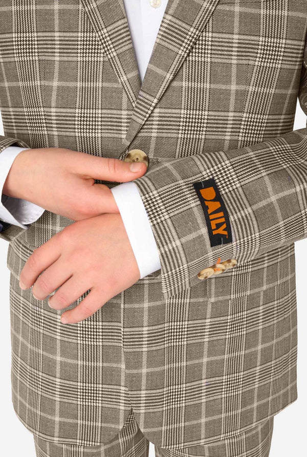 Close-up of a person wearing a tan checkered suit with a Daily label on the sleeve.