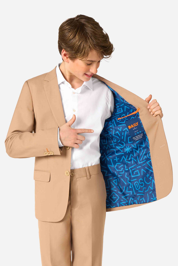 Teen boy wearing a stylish light brown/ beige suit with a white dress shirt, looking confidently in the camera. Perfect formal outfit for boys' special occasions, weddings, and parties. Holding one side of the jacket open.