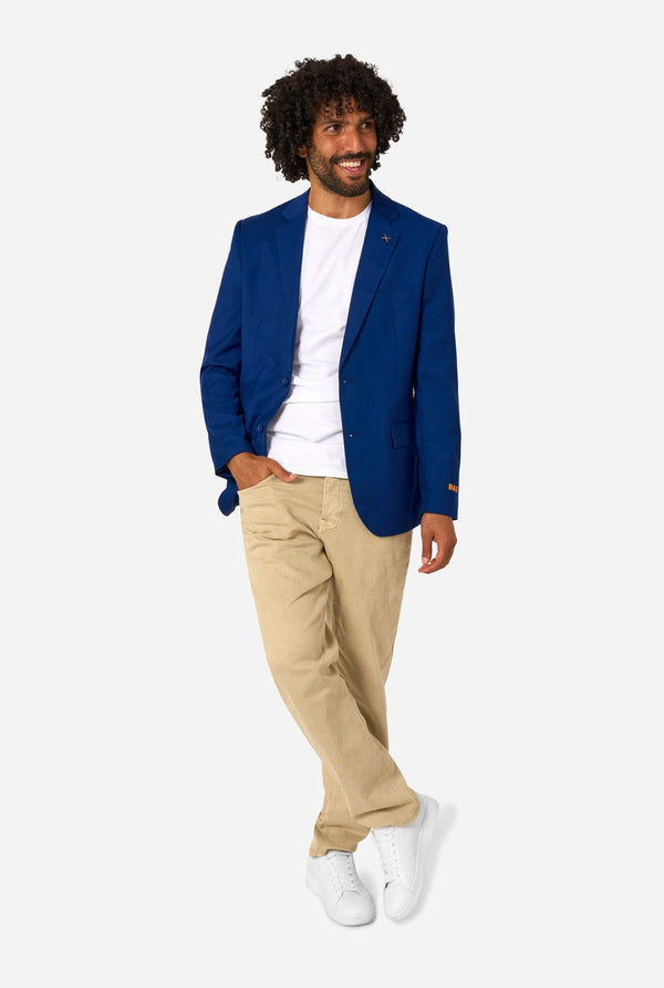 Man wearing a blue blazer, white shirt, beige pants, and white sneakers on a white background. Full body image