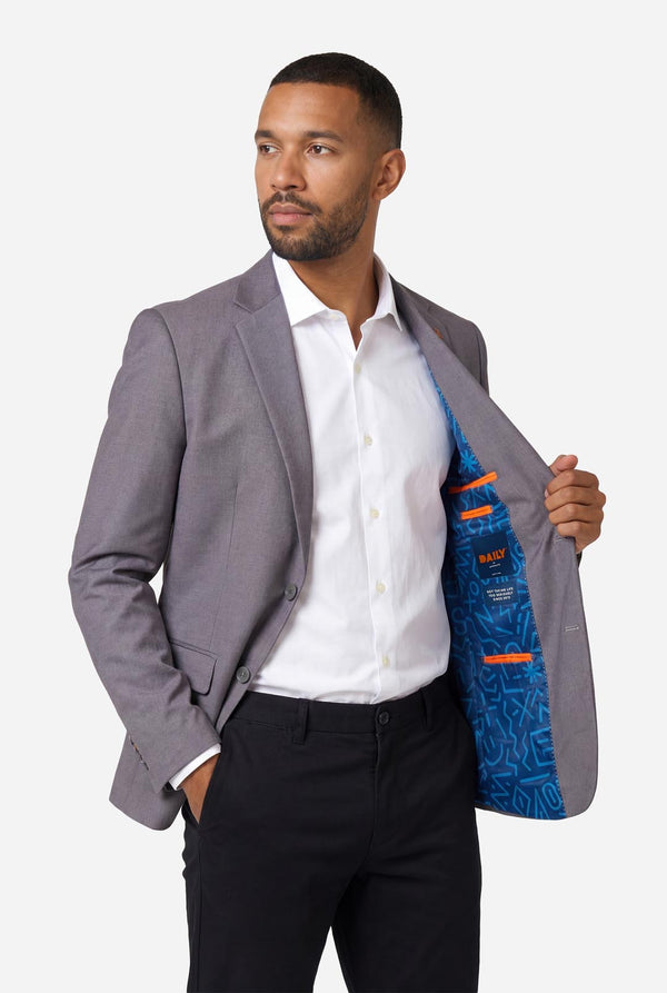 Man wearing a gray blazer with a blue pattern inside, on a white background