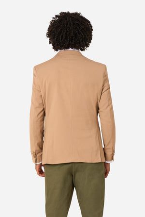 Person wearing a beige blazer and green pants on a white background. View from the back