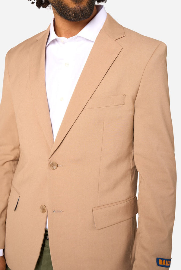 Beige suit jacket worn by a person on a white background. Close up of the chest