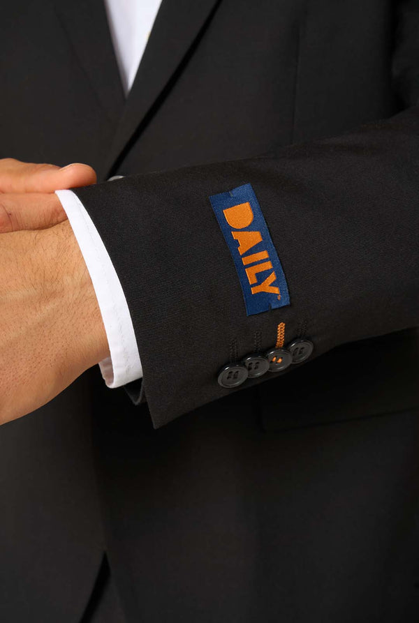 Close-up of a suit cuff with a 'Daily' logo on a dark suit jacket.