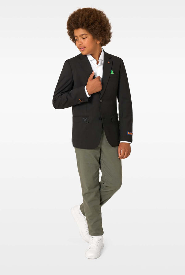 Person wearing a black blazer, white shirt, and green pants on a white background. Full body image