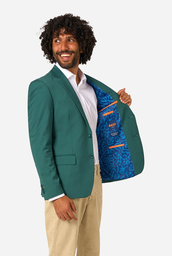 Man wearing a green blazer with a blue interior lining, holding the blazer open to reveal the interior.