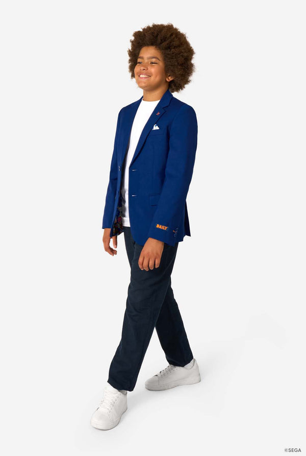 Person wearing a blue blazer with a Sonic logo, white shirt, navy pants, and white sneakers on a white background. Full body image