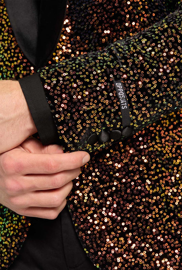 Close-up of a sequined sleeve with a brand label, held by a hand.