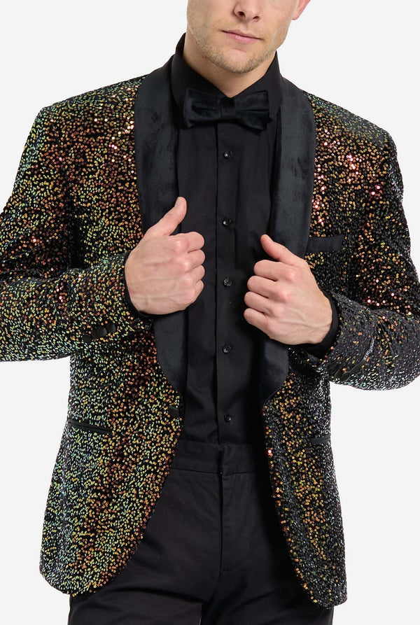 Man wearing a sequin blazer over a black shirt and bow tie on a white background