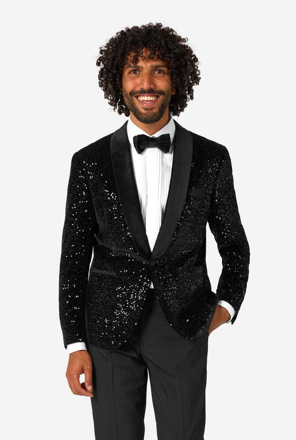 Man wearing a black sequin tuxedo with a white shirt and bow tie on a white background