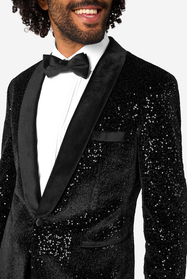 Man wearing a black sequin tuxedo with a bow tie on a white background