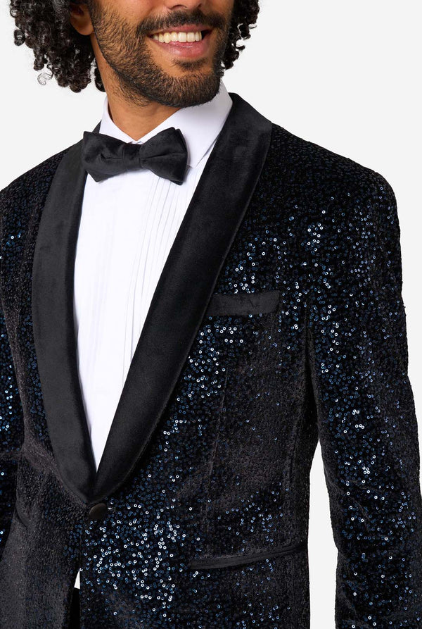 Man wearing a navy sequin tuxedo with a bow tie on a white background