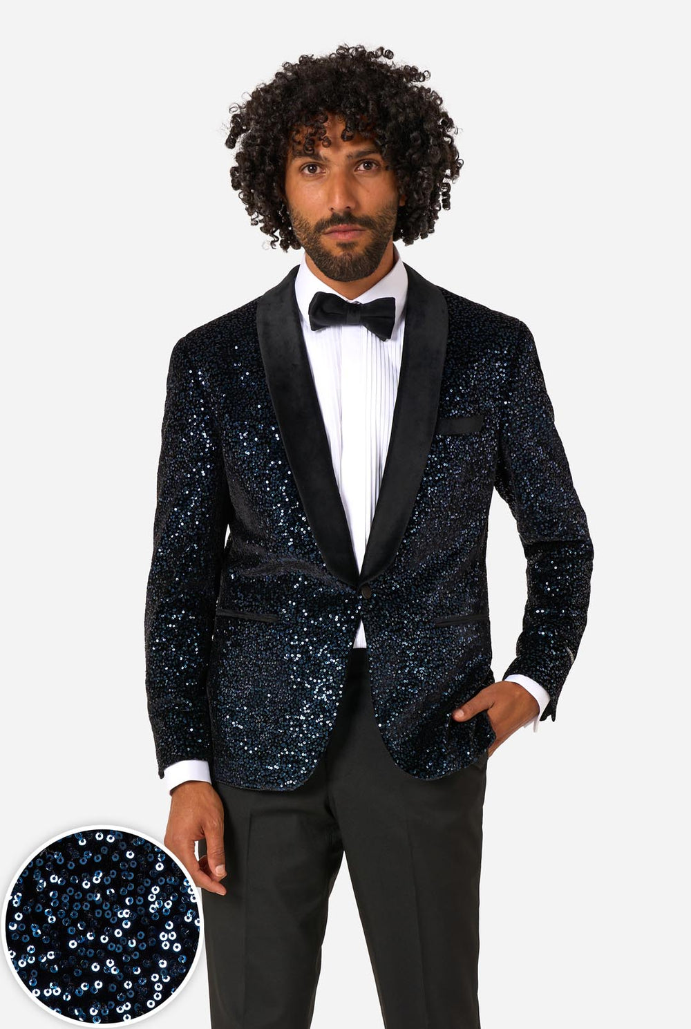 Man wearing a navy sequin tuxedo with a white shirt and bow tie on a light gray background.