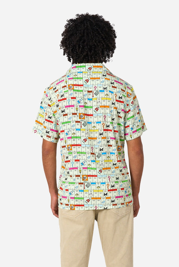 Person wearing a colorful Monopoly patterned shirt on a white background. View from the back