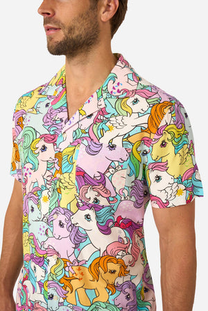 Man wearing a colorful My Little Pony shirt with cartoon unicorn design on a plain background