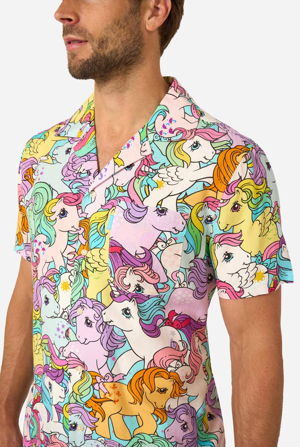 Man wearing a colorful My Little Pony shirt with cartoon unicorn design on a plain background