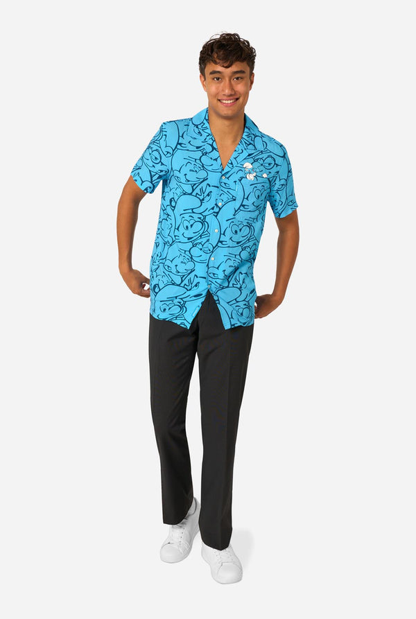 Person wearing a blue Smurfs patterned shirt and black pants on a white background. Full body image
